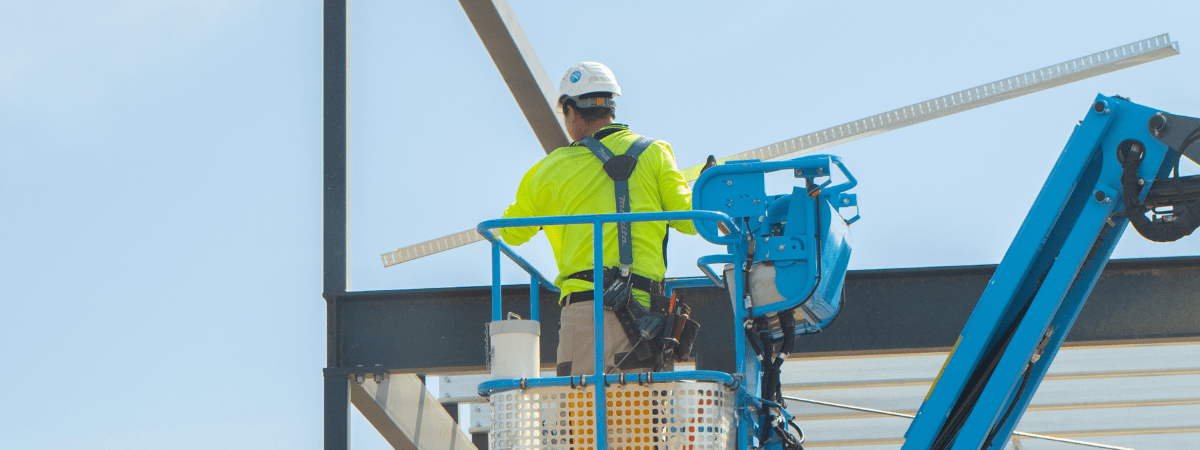 man in hi-vis working on a building frame in a scissor lift