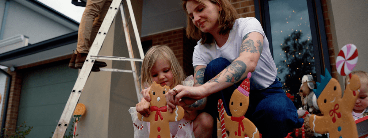 mum and daughter put gingerbread man decorations in their front yard